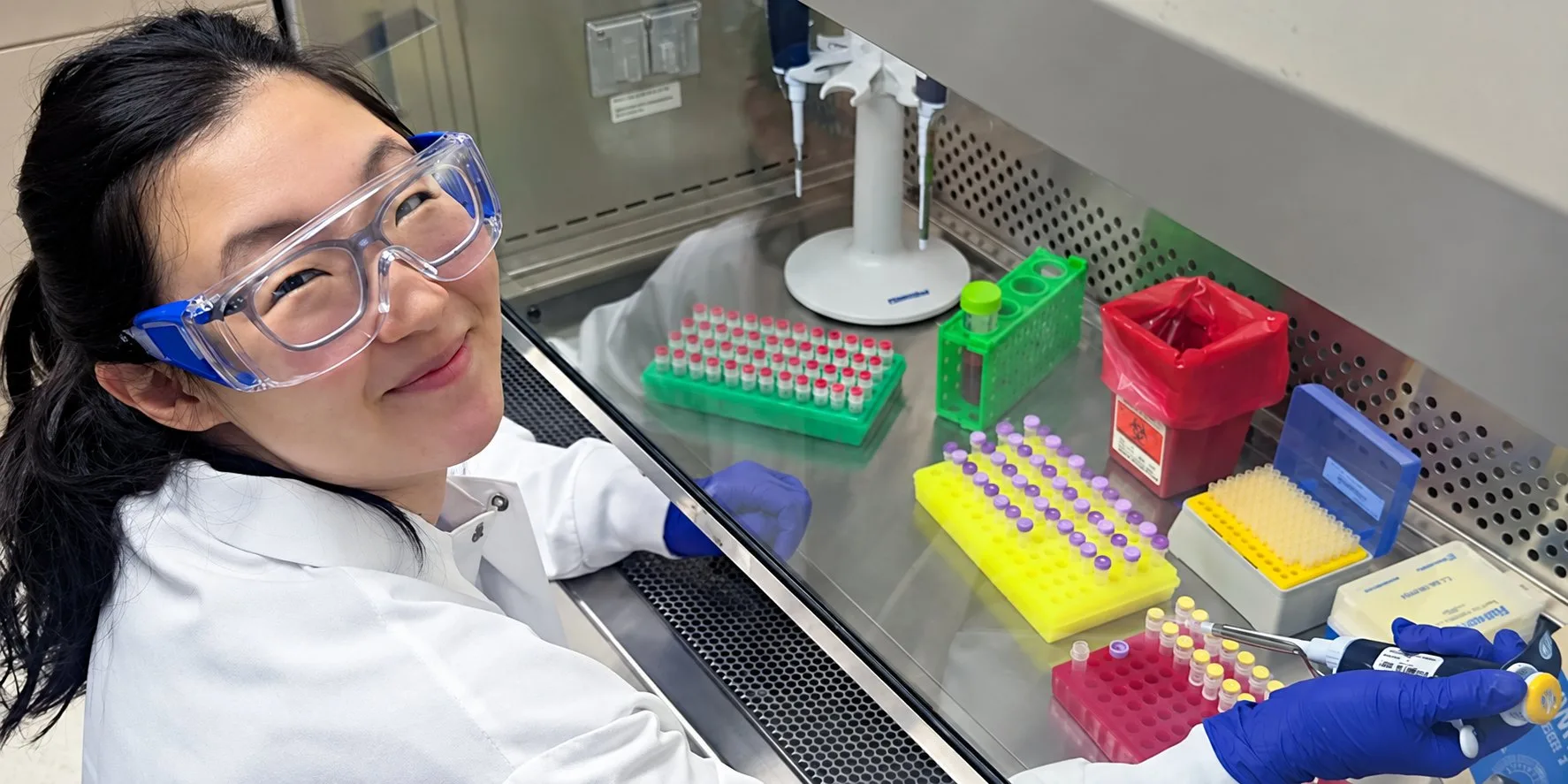 BRI researcher at a biosafety cabinet with sample tube racks