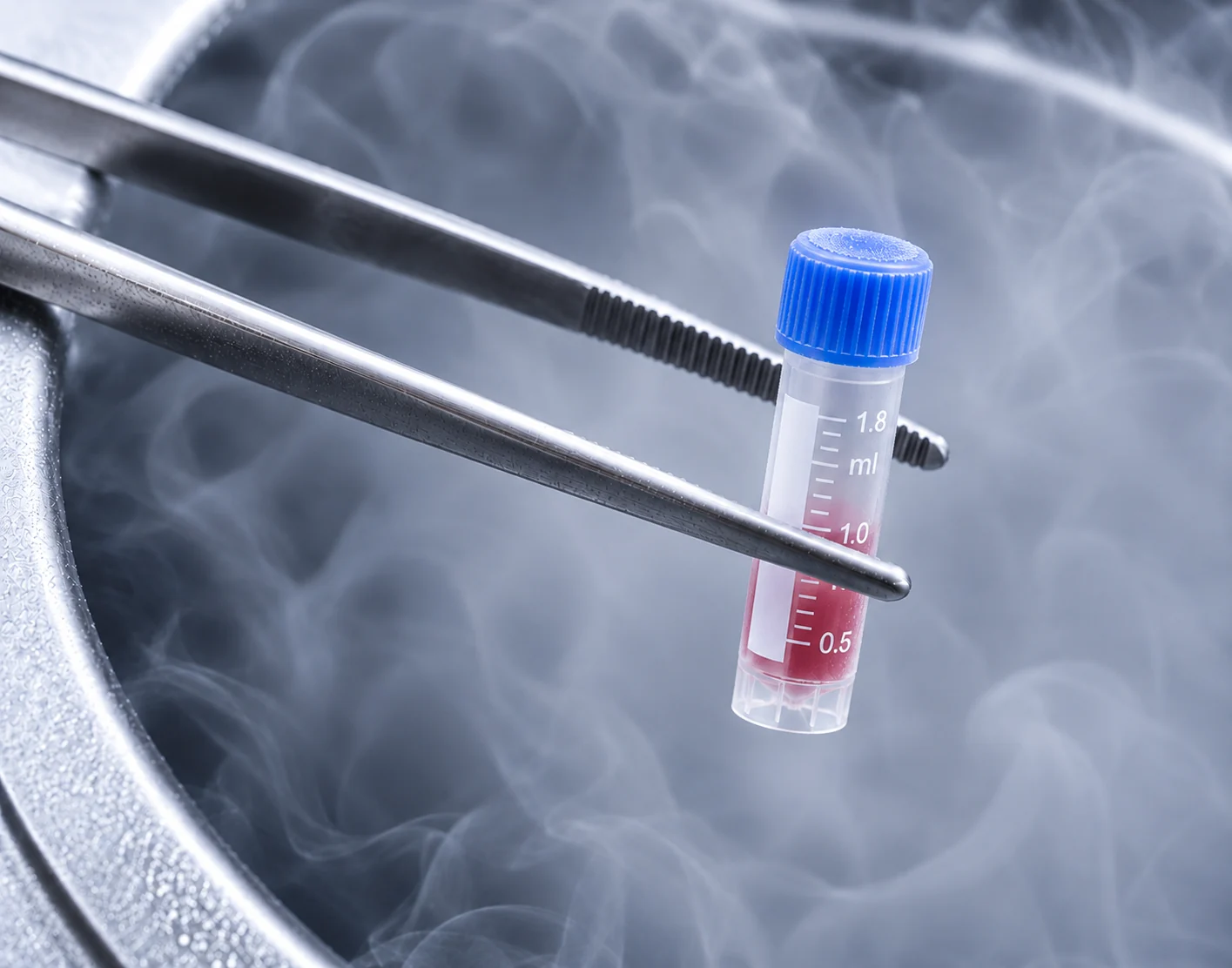 Forceps holding a sample vial above a cryogenic storage vessel